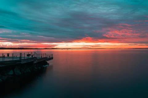 Dramatic storm clouds and glowing sunset over Finnish lake Stock Photos