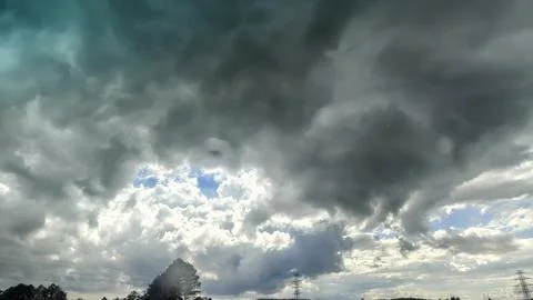 Dramatic storm clouds gather, breaking to reveal patches of blue sky Stock Photos