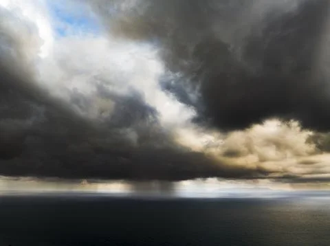 Dramatic storm clouds gather over the dark ocean with rain falling in the d.. 写真素材