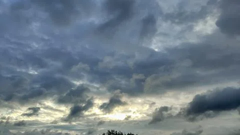 Dramatic storm clouds gather with sunlight breaking through the overcast sky Stock Photos