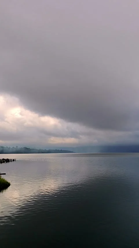 Dramatic Storm Clouds Gathering Over Calm Lake Water at Sunrise Stock Footage 340626600