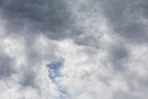 Dramatic storm clouds gathering in the sky with hints of blue peeking through Stock Photos