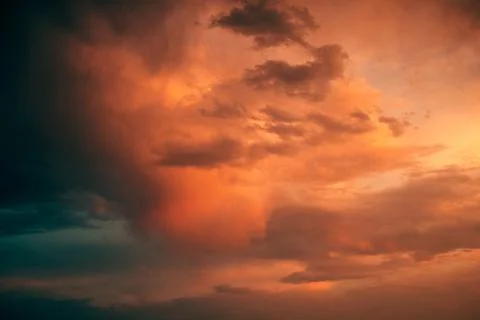 Dramatic storm clouds glowing orange and red beneath intense evening light,.. Stock Photos