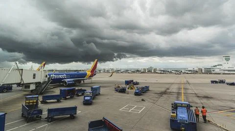Dramatic Storm clouds hang over gate at airport as plane sits on tarmac 스톡 사진