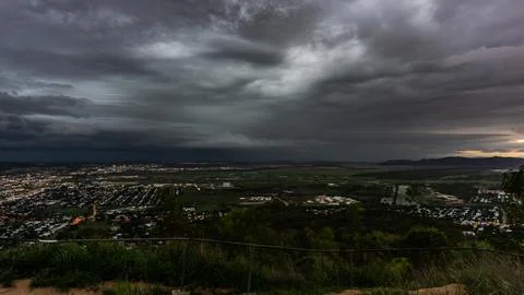 Dramatic storm clouds loom over a bustling urban landscape at dusk, creatin.. Stock Photos