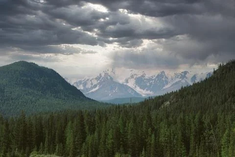 Dramatic storm clouds over Altai Mountains with sun rays and snowy peaks 스톡 사진