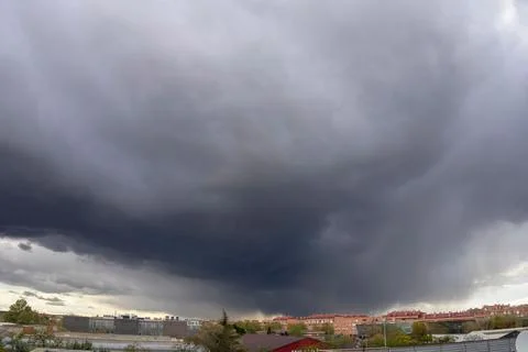 Dramatic storm clouds over a cityscape with buildings and trees in the Fotos de archivo