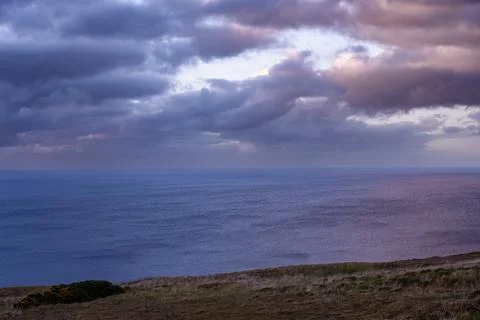 Dramatic storm clouds over coastal hills and ocean, dark sky and moody nature la Stock Photos