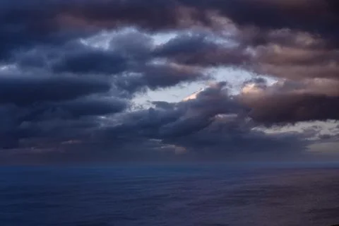 Dramatic storm clouds over coastal hills and ocean, dark sky and moody nature la Stock Photos