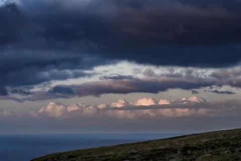 Dramatic storm clouds over coastal hills and ocean, dark sky and moody nature la Stock Photos