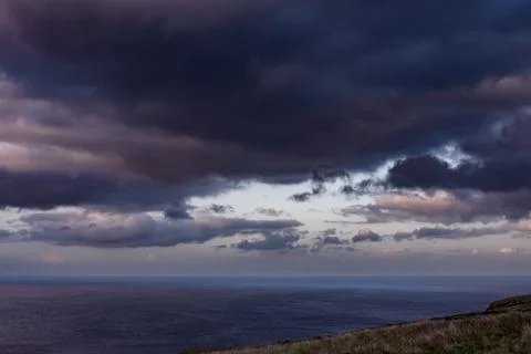 Dramatic storm clouds over coastal hills and ocean, dark sky and moody nature la Stock Photos
