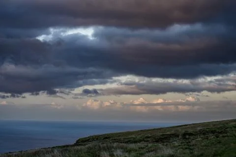 Dramatic storm clouds over coastal hills and ocean, dark sky and moody nature la Stock Photos