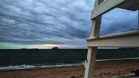 Dramatic storm clouds over dark ocean waves from a beach lifeguard chair during Vídeo Stock 346049187