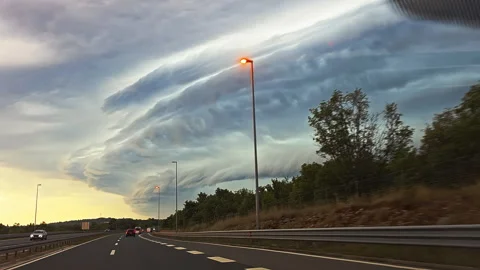 Dramatic storm clouds over highway at sunset. Massive shelf cloud formation Stock Footage 316549246