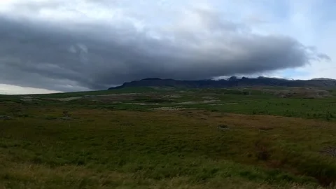 Dramatic storm clouds over Icelandic green fields and mountains Stock Footage 334134662