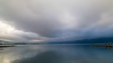 Dramatic Storm Clouds Over Peaceful Lake with Wooden Dock Fotos de archivo