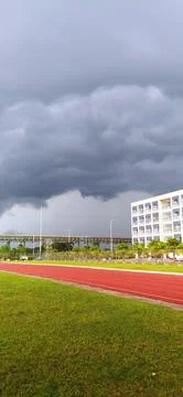 Dramatic storm clouds over red athletic running track and field 스톡 사진