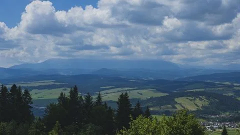 Dramatic Storm Clouds Over Rolling Green Hills and Forested Mountain Landscape Photos
