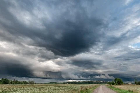 Dramatic Storm Clouds Over a Rural Landscape With a Dirt Road Foto stock