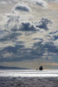 Dramatic storm clouds over sea with small boat silhouette Stock Photos