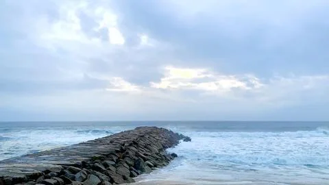 Dramatic storm clouds over the sea and breakwater at Furadouro beach in Por.. Stock Photos