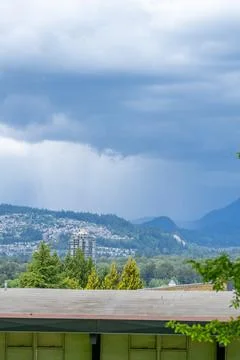Dramatic storm clouds over suburban Vancouver with mountains in the backgroun Stock Photos