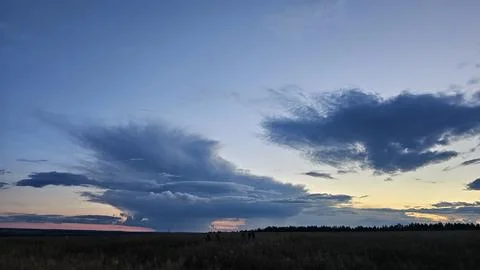 Dramatic storm clouds over wheat field at sunset, breathtaking evening sky with Stock Photos