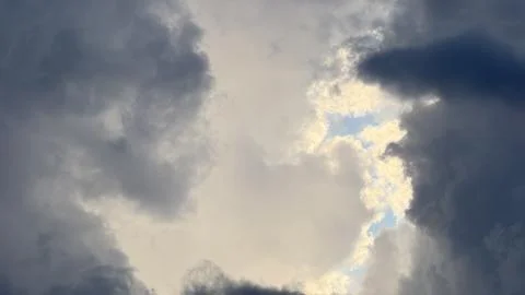 Dramatic storm clouds parting to reveal a central glowing opening with bright Stock Photos