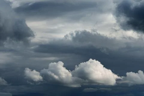 Dramatic storm clouds before rain with contrasting white and dark grey layers. Stock Photos
