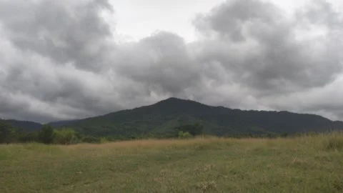 Dramatic Storm Clouds Rolling Over Mountain Range and Green Meadow Stock Footage 342952519