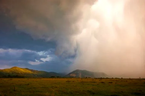Dramatic storm landscape with clouds and rain in sunset light Stock Photos
