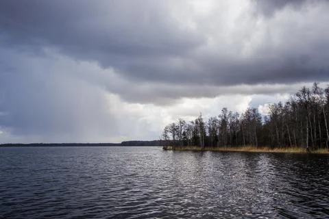 Dramatic storm over a dark lake. Ominous clouds and choppy water create a pow Фото