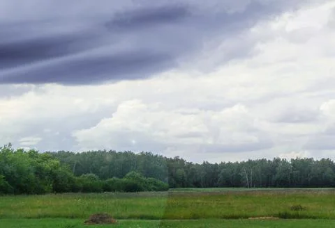 Dramatic storm scene with gray clouds in the field, sunlight breaking through Stock Photos