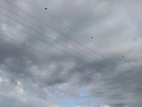 Dramatic stormy clouds loom over power lines, creating a moody and atmospheric 스톡 사진