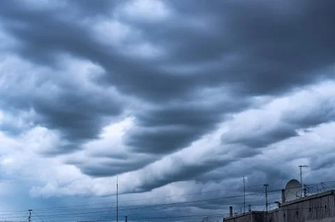 Dramatic Stormy Clouds over the High-Rise Rooftop with Cable Wires Stock Photos