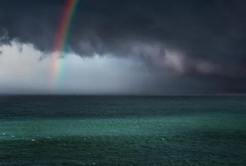 Dramatic stormy clouds over the sea with a rainbow Stock Photos