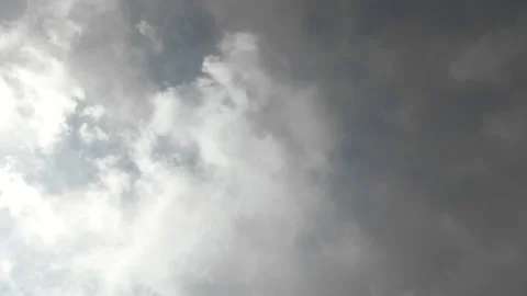 Dramatic stormy cloudscape with dark gray clouds passing over the sun against a 스톡 동영상 345097631