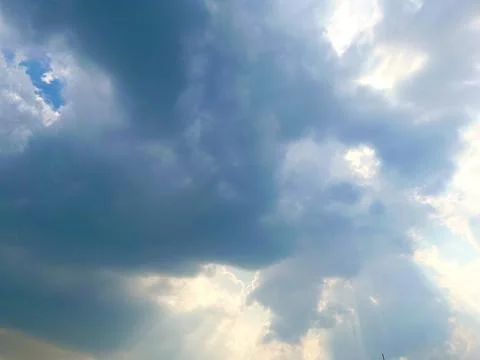 Dramatic stormy sky with bright sunlight breaking through dark clouds Stock Photos