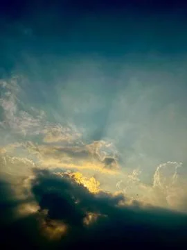 Dramatic stormy sky with golden sunlight breaking through dark clouds Stock Photos