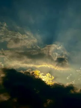 Dramatic stormy sky with golden sunlight breaking through dark clouds Stock Photos