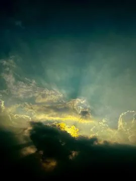 Dramatic stormy sky with golden sunlight breaking through dark clouds Stock Photos