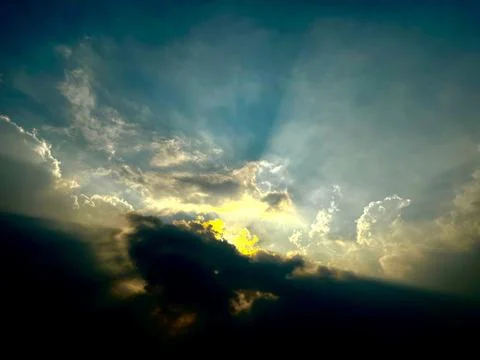 Dramatic stormy sky with golden sunlight breaking through dark clouds Stock Photos