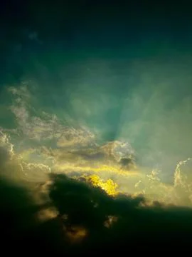 Dramatic stormy sky with golden sunlight breaking through dark clouds Stock Photos
