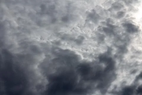 Dramatic stormy sky with heavy dark rain clouds covering bright sunlight Stock Photos