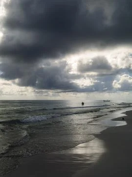 Dramatic stormy sky over Caribbean beach with silhouetted couple wading in .. Foto stock