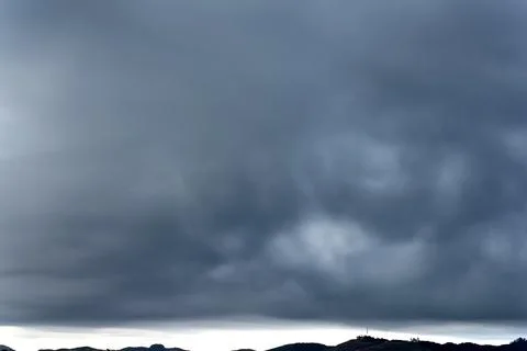 Dramatic stormy sky over mountain range with communication tower Stock Photos