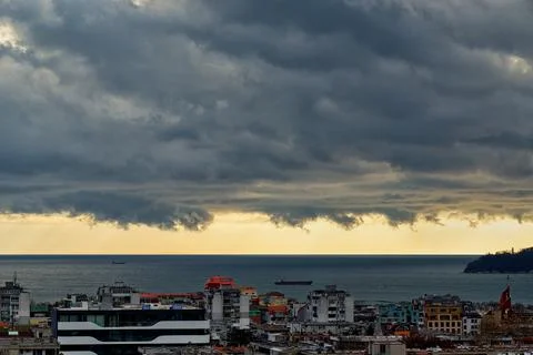 Dramatic stormy sky over small seaside city. Yellow sky just before the storm. Stock Photos