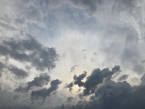 A dramatic, stormy sky scene with sunlight piercing through dark gray cloud.. Stock Photos