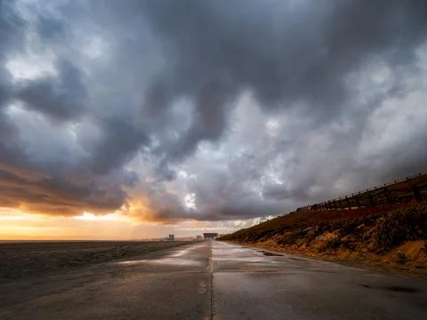 Dramatic stormy sunset over a wet coastal road with dramatic clouds Foto stock