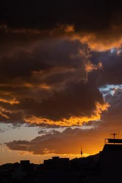 Dramatic stormy sunset sky with orange heavy clouds over city skyline. Photos